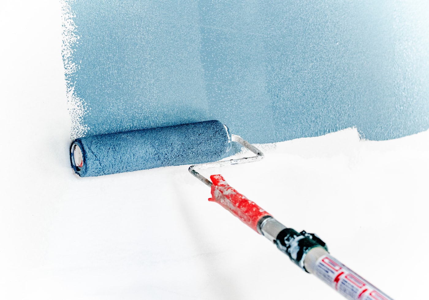 A roller laying blue-grey paint across a wall